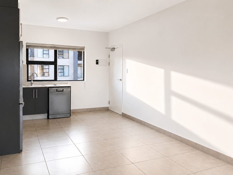 A clean, modern kitchen area featuring dark cabinetry, tiled flooring, and an integrated dishwasher, offering a bright and functional space.