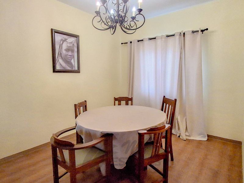 A functional dining room featuring laminate flooring and a central chandelier, providing a neutral space ready for personalization.