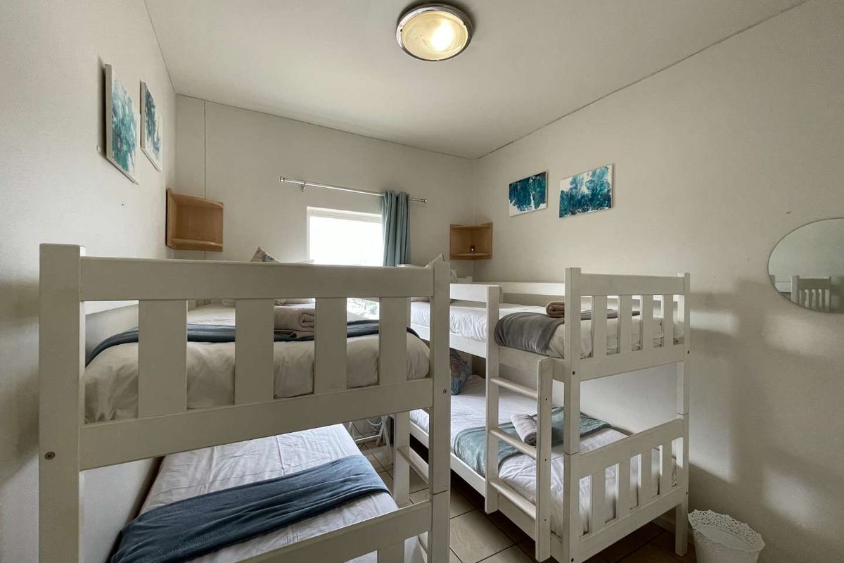 A functional bedroom featuring tiled flooring and built-in corner shelving, currently configured with bunk beds to maximize sleeping capacity.