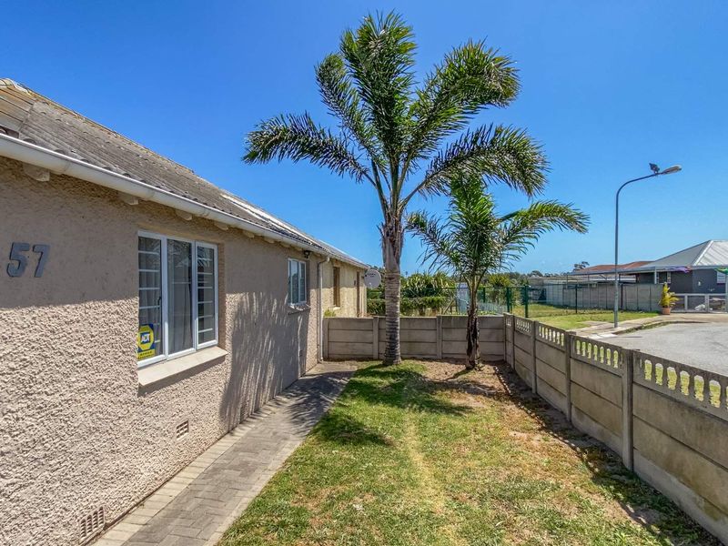 Front exterior view of the property featuring a paved walkway, stucco facade, and a precast concrete boundary wall.