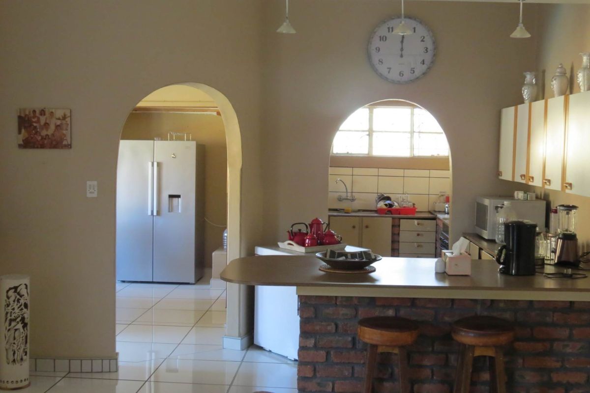 A kitchen featuring a brick-base breakfast bar, arched doorways, tiled flooring, and built-in cabinetry with a functional layout.