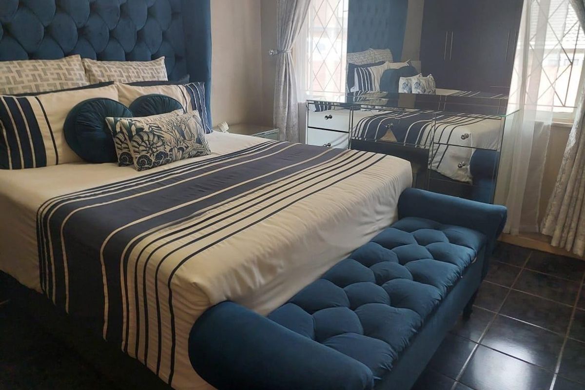 A well-appointed bedroom featuring dark tiled flooring and a built-in mirrored wardrobe, creating a cohesive and stylish living space.