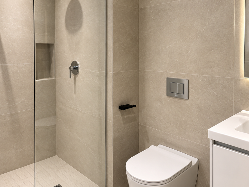 Modern bathroom featuring a walk-in shower with a rain shower head, a wall-mounted toilet, and a sleek vanity cabinet with integrated sink.