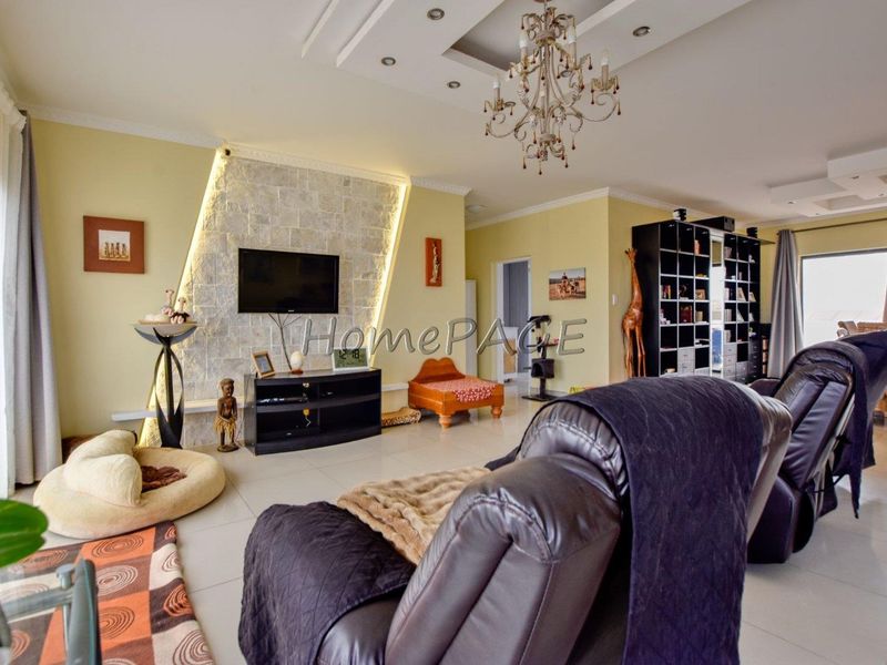 Spacious living room featuring a stone accent wall with integrated lighting, recessed ceiling details, and tiled flooring.
