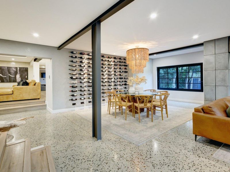 Spacious open-plan living and dining area featuring polished terrazzo flooring, a striking built-in wine display wall, and modern architectural steel detailing.