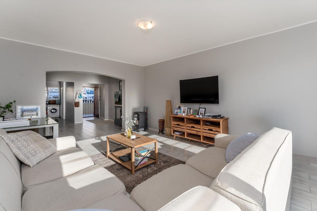 A bright living room featuring tiled flooring and an open archway leading to the utility area, providing a functional and connected living space.