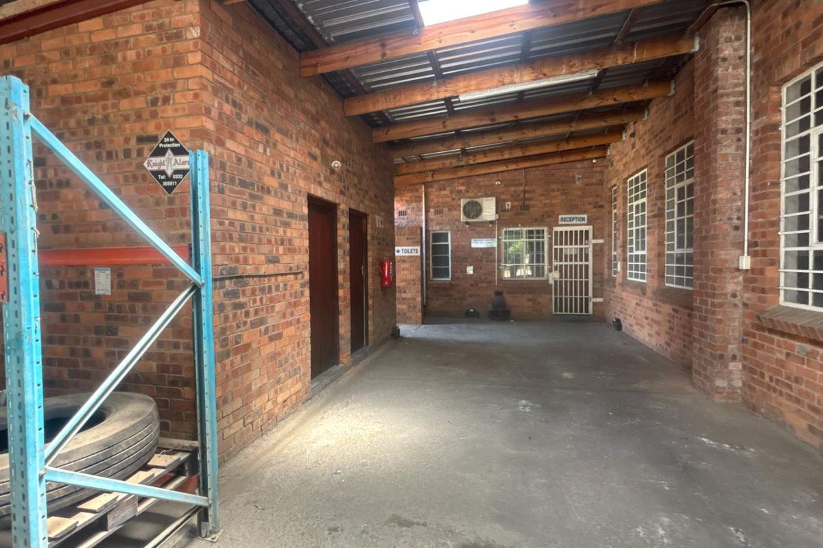 A functional industrial utility space featuring exposed brick walls, timber roof trusses, and concrete flooring, with secure access points and integrated air conditioning.