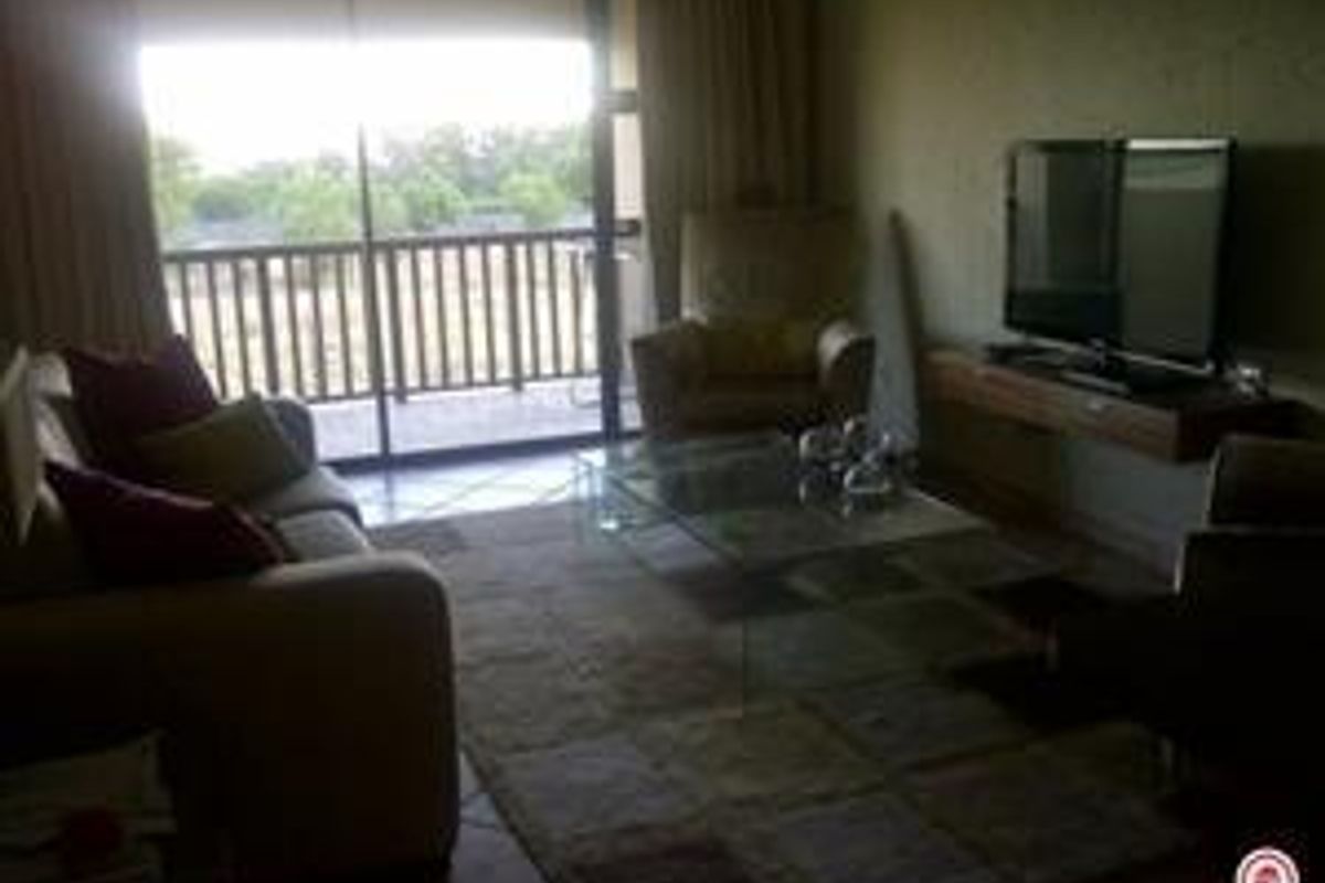 A living room featuring tiled flooring, a floating media console, and a large sliding glass door providing access to an outdoor balcony area.