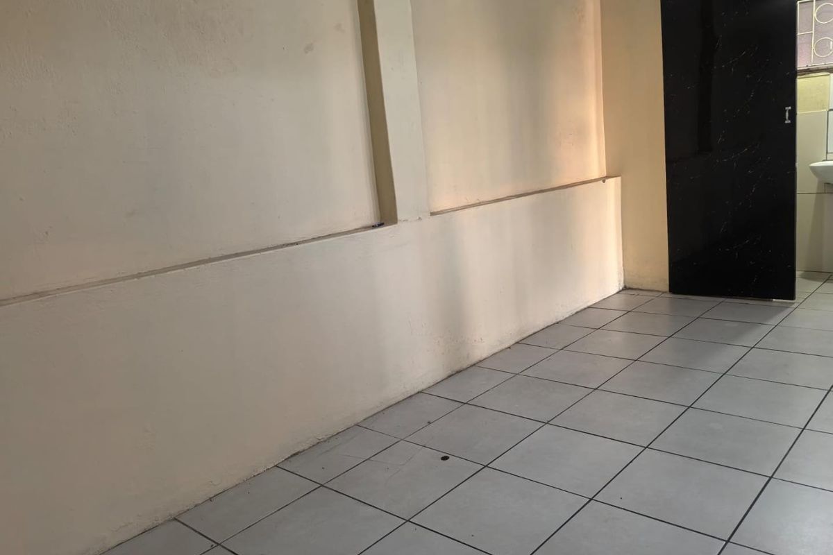 An empty living area featuring neutral wall finishes and ceramic floor tiles, providing a blank canvas for interior design.