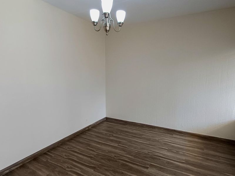 A clean, empty bedroom featuring modern laminate flooring, neutral walls, and fitted venetian blinds, ready for personalization.