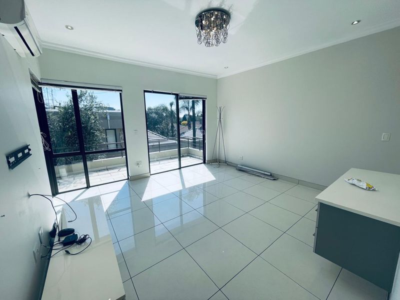 Bright and spacious living area featuring large sliding glass doors leading to a balcony, polished tile flooring, and modern recessed lighting.