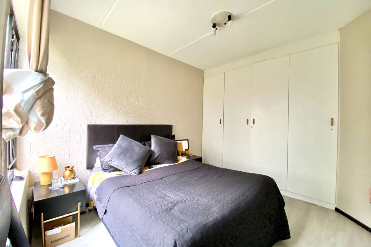 A bedroom featuring built-in floor-to-ceiling wardrobes and light-toned flooring, providing ample storage space.