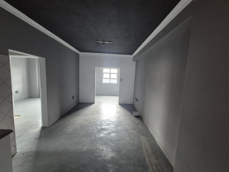An empty living area featuring dark painted ceilings, crown molding, and concrete flooring, offering a blank canvas for interior design.