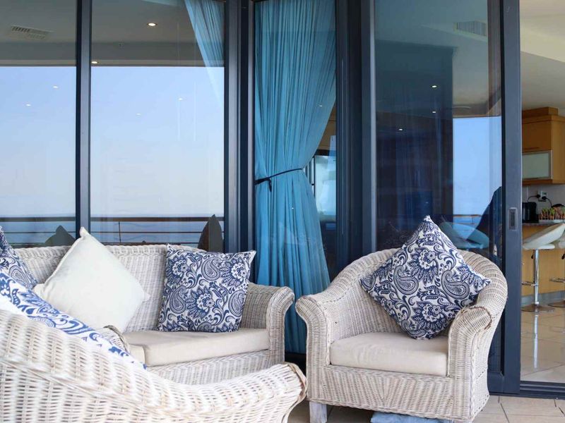 A view from a covered balcony looking into an open-plan living and kitchen area with large sliding glass doors.