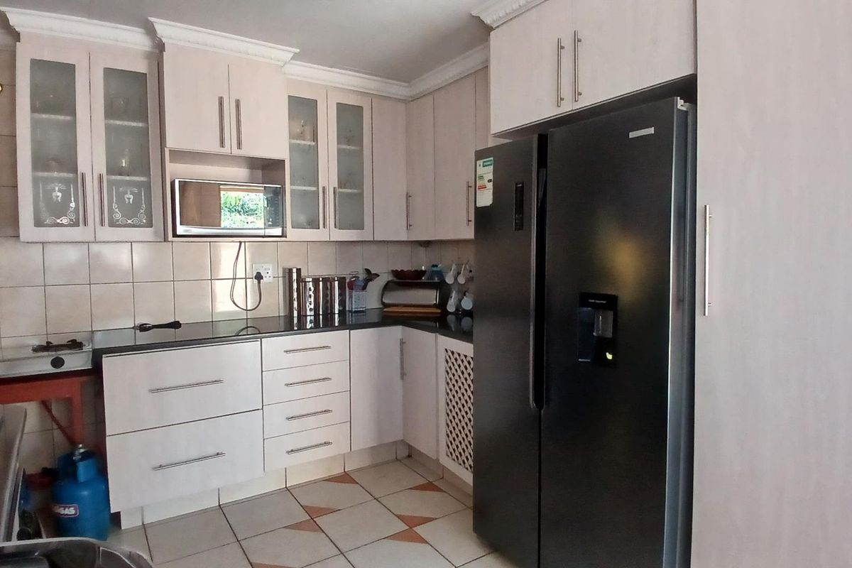A functional kitchen featuring built-in cabinetry, granite countertops, a tiled backsplash, and a gas hob, offering practical storage and workspace.