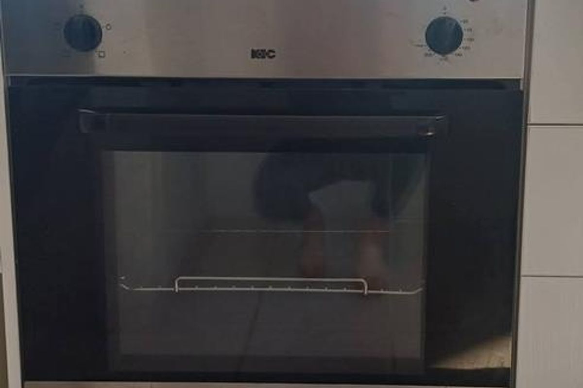 A kitchen area featuring a built-in oven and hob, currently undergoing renovation with unfinished wall surfaces and missing trim.