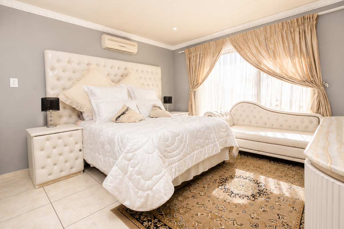 A well-maintained bedroom featuring tiled flooring, crown molding, and a wall-mounted air conditioning unit.