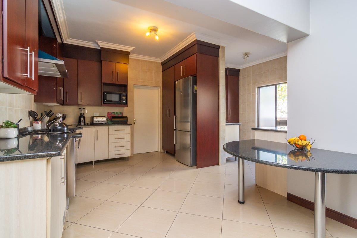 Spacious kitchen featuring dark wood cabinetry, granite countertops, a breakfast bar, and tiled flooring with integrated appliances.