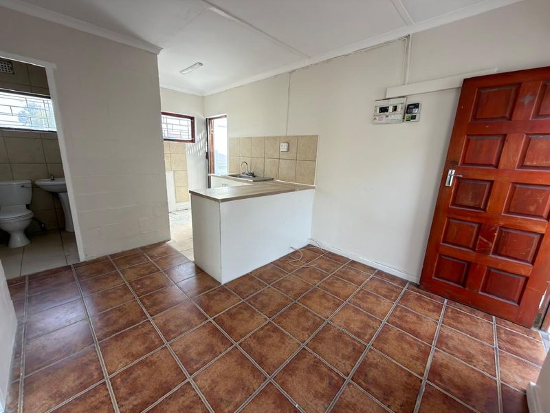 Open plan living area featuring tiled flooring, a compact kitchen sink area, and direct access to an adjacent bathroom.