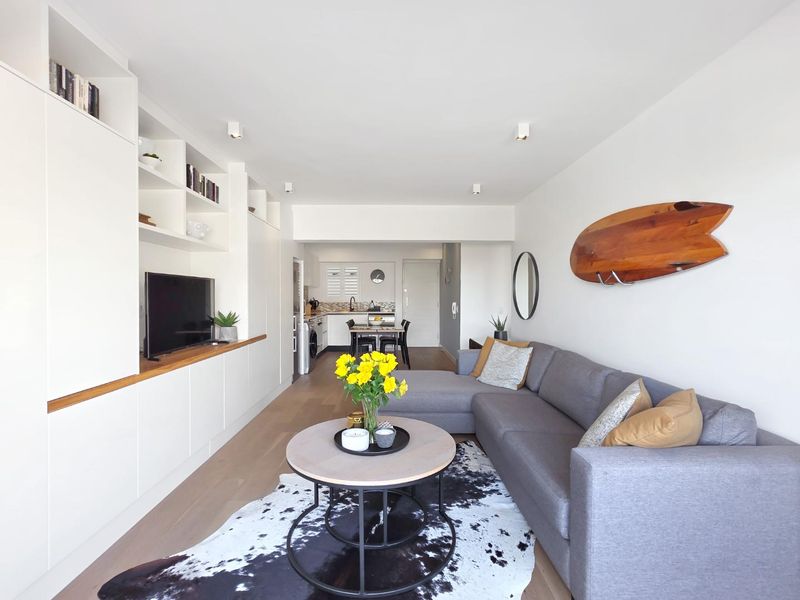 Bright open-plan living area featuring modern built-in cabinetry, hardwood flooring, and a functional kitchen space with clean finishes.