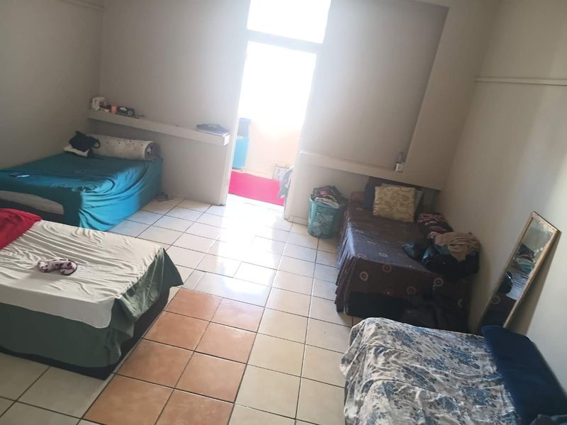 A spacious bedroom featuring tiled flooring, built-in shelving, and direct access to an outdoor balcony area.