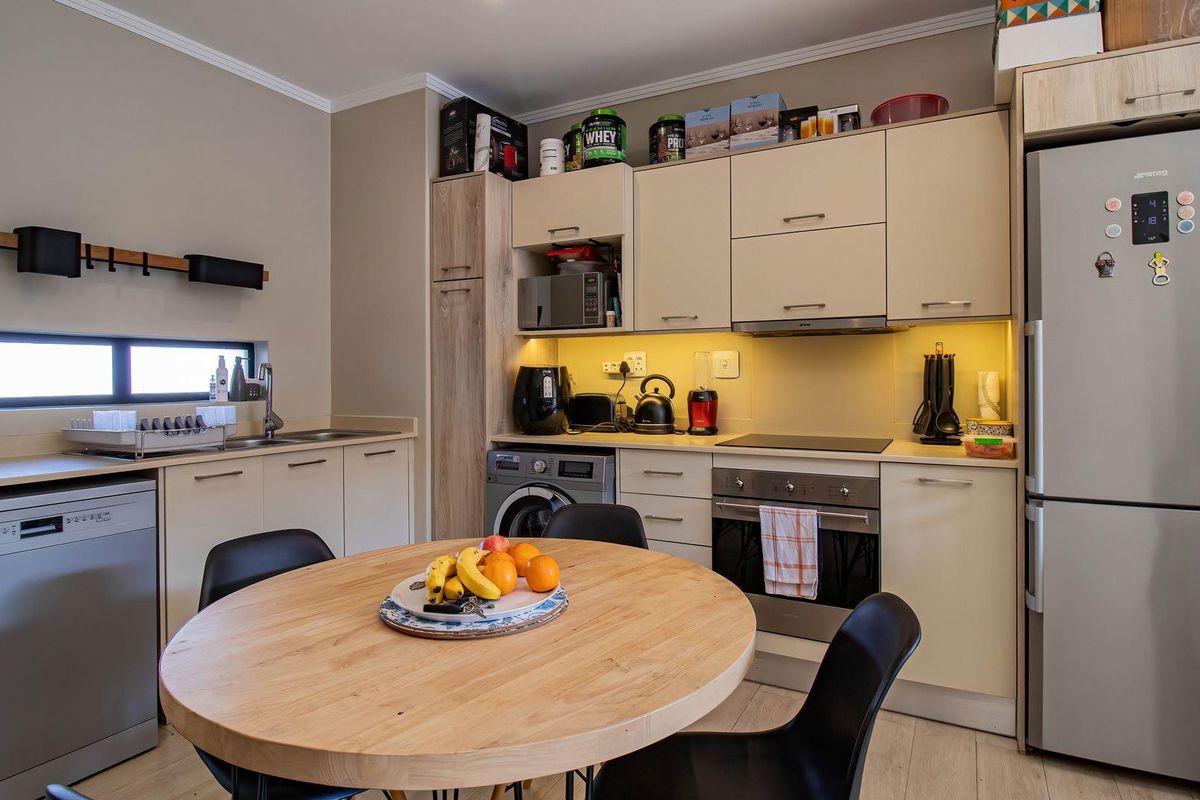 Modern kitchen featuring sleek cabinetry, integrated appliances, under-cabinet lighting, and a functional layout with a dedicated dining area.