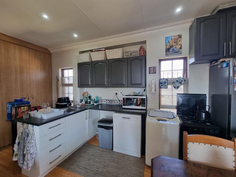 A functional kitchen featuring dark and white cabinetry, laminate countertops, a double basin sink, and integrated appliances, offering a practical layout for daily use.