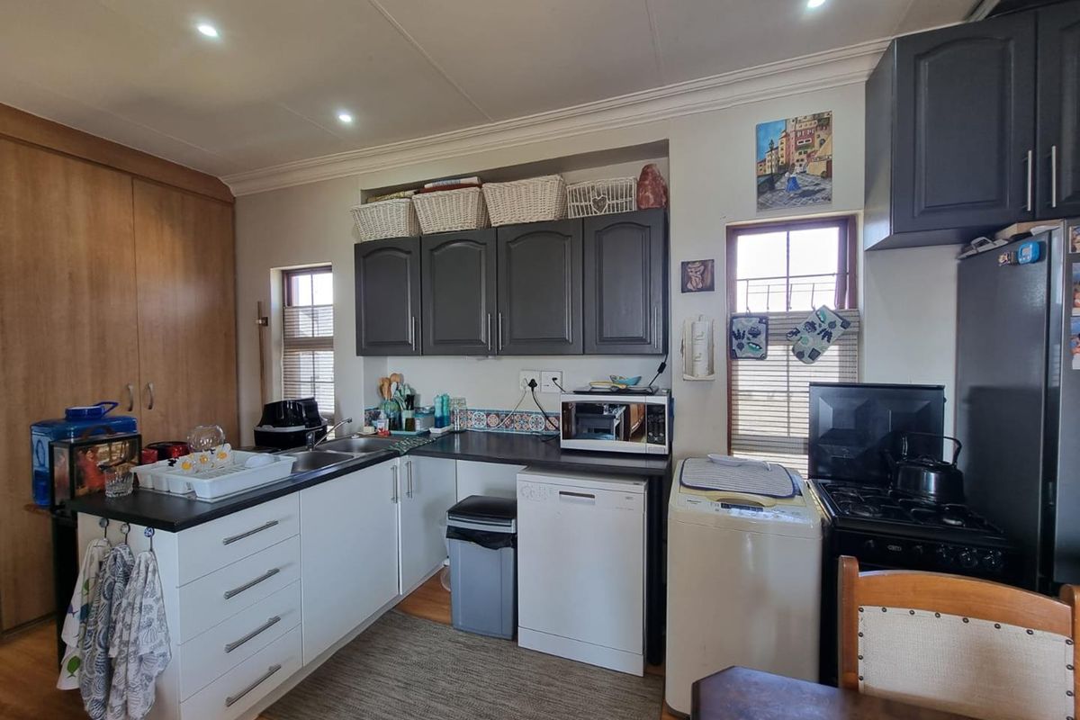 A functional kitchen featuring dark and white cabinetry, laminate countertops, a double basin sink, and integrated appliances, offering a practical layout for daily use.