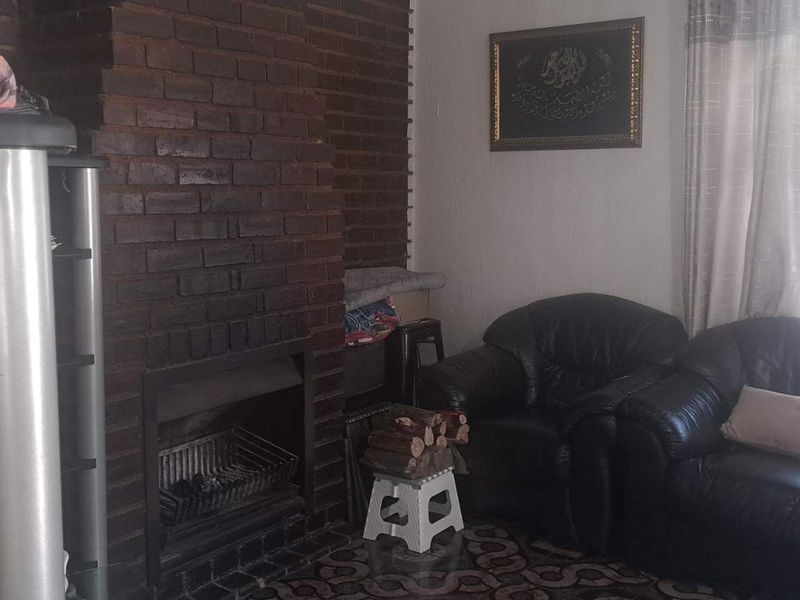 A living room featuring a prominent dark brick fireplace and hearth, providing a focal point for the space.