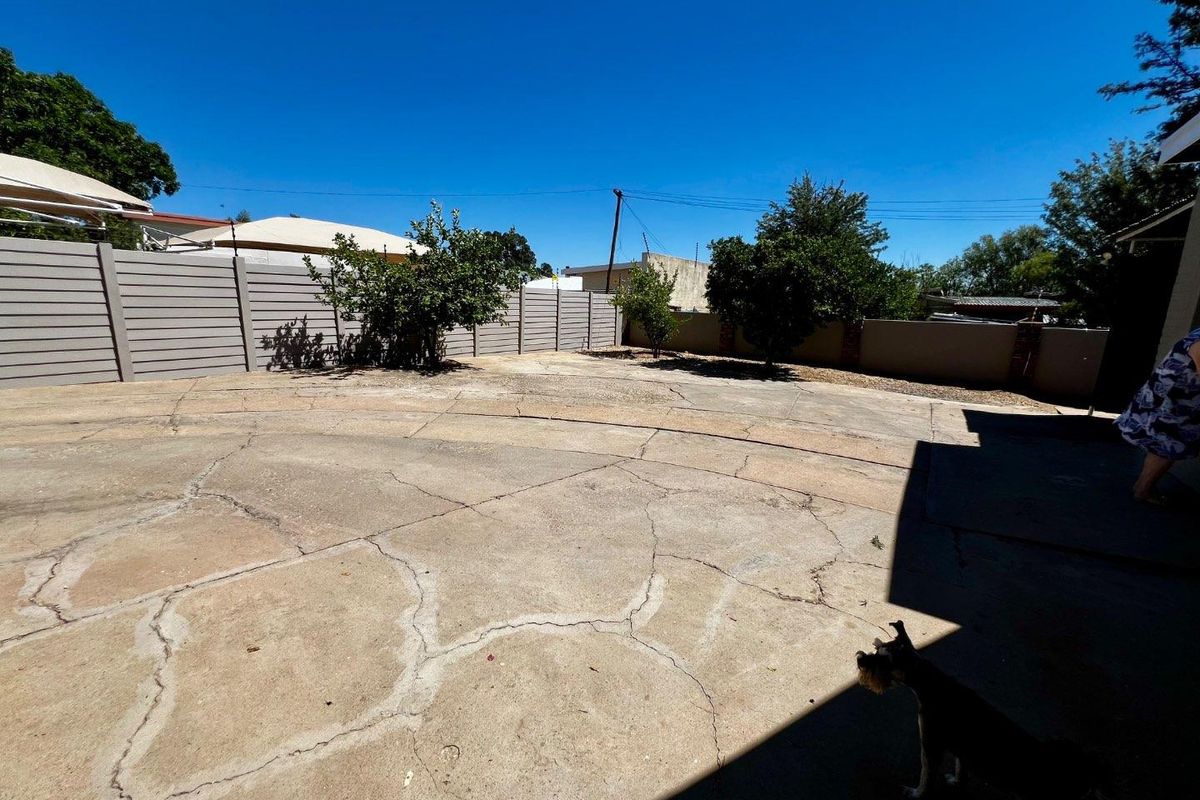 A spacious outdoor paved area enclosed by perimeter fencing, featuring significant surface cracking throughout the concrete.