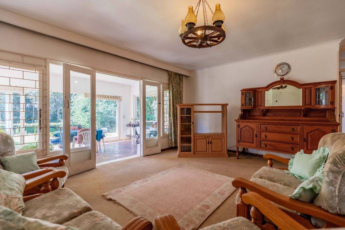 A spacious living room featuring large glass doors that open onto a covered patio, providing natural light and garden views.