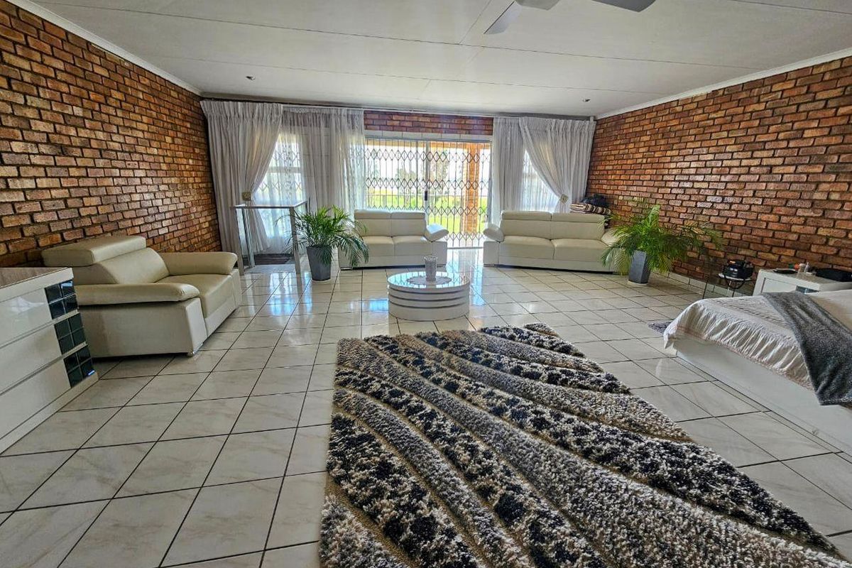 Spacious living room featuring exposed brick walls, ceramic tiled flooring, and a ceiling fan, with direct access to the outdoor area via sliding doors.