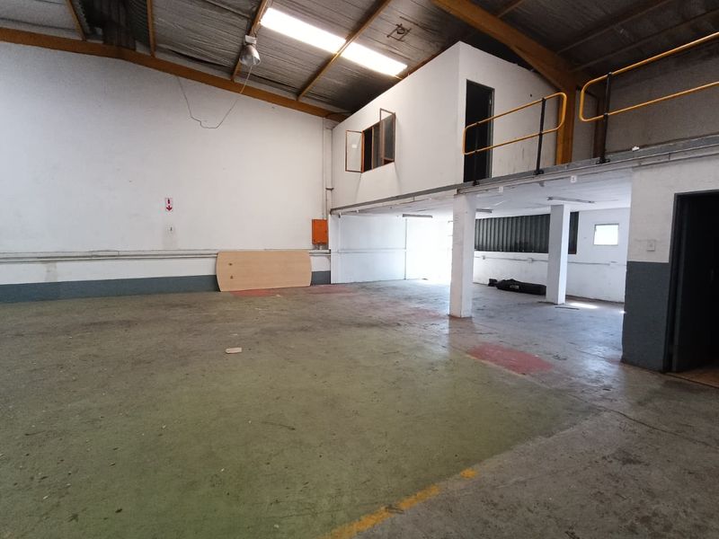 Spacious industrial warehouse unit featuring a mezzanine level, exposed structural elements, concrete flooring, and functional open-plan layout suitable for various commercial or storage uses.