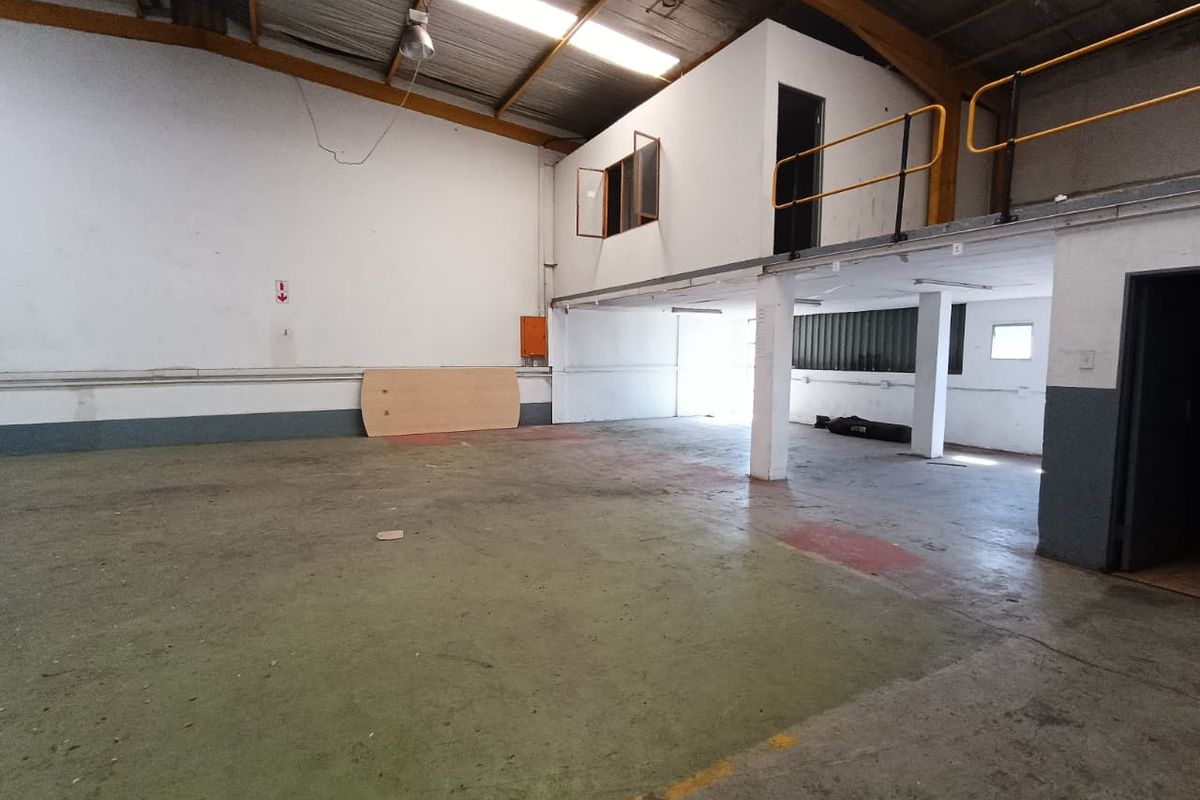 Spacious industrial warehouse unit featuring a mezzanine level, exposed structural elements, concrete flooring, and functional open-plan layout suitable for various commercial or storage uses.