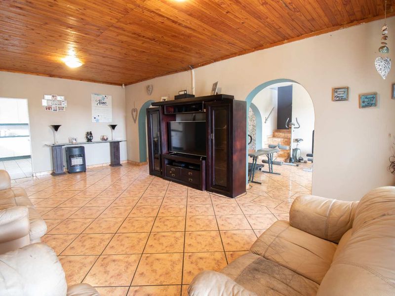 Spacious living room featuring a timber-clad ceiling, ceramic tiled flooring, and an arched entryway leading to an adjacent area.