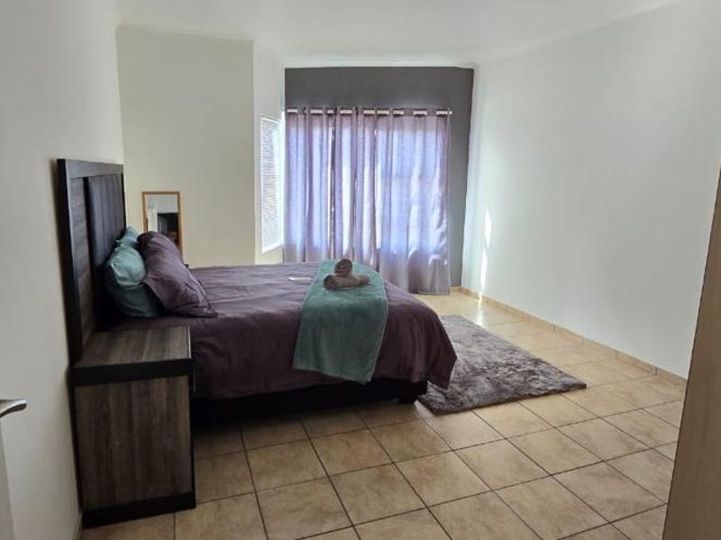 A bedroom featuring tiled flooring and a neutral color palette, offering a functional space with natural light from the window.