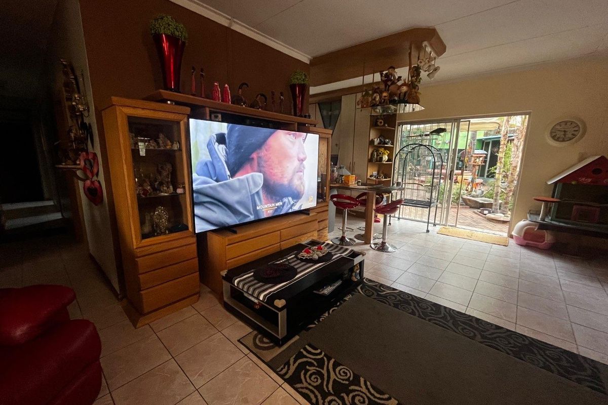 A living room featuring tiled flooring, built-in cabinetry, and a sliding glass door providing access to an outdoor patio area.