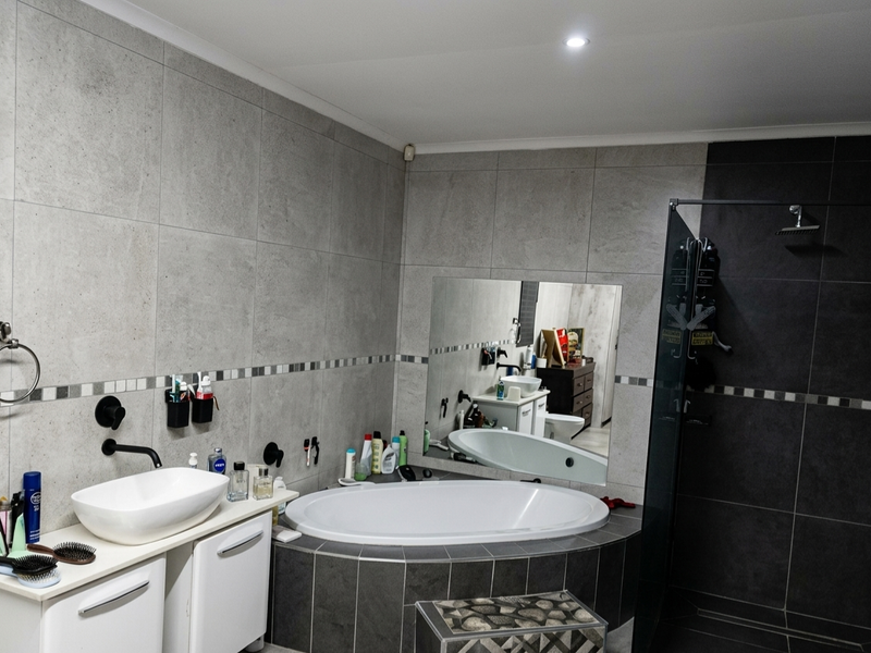 Modern bathroom featuring a tiled walk-in shower, a built-in bathtub with dark tile surround, and a contemporary vessel sink vanity.