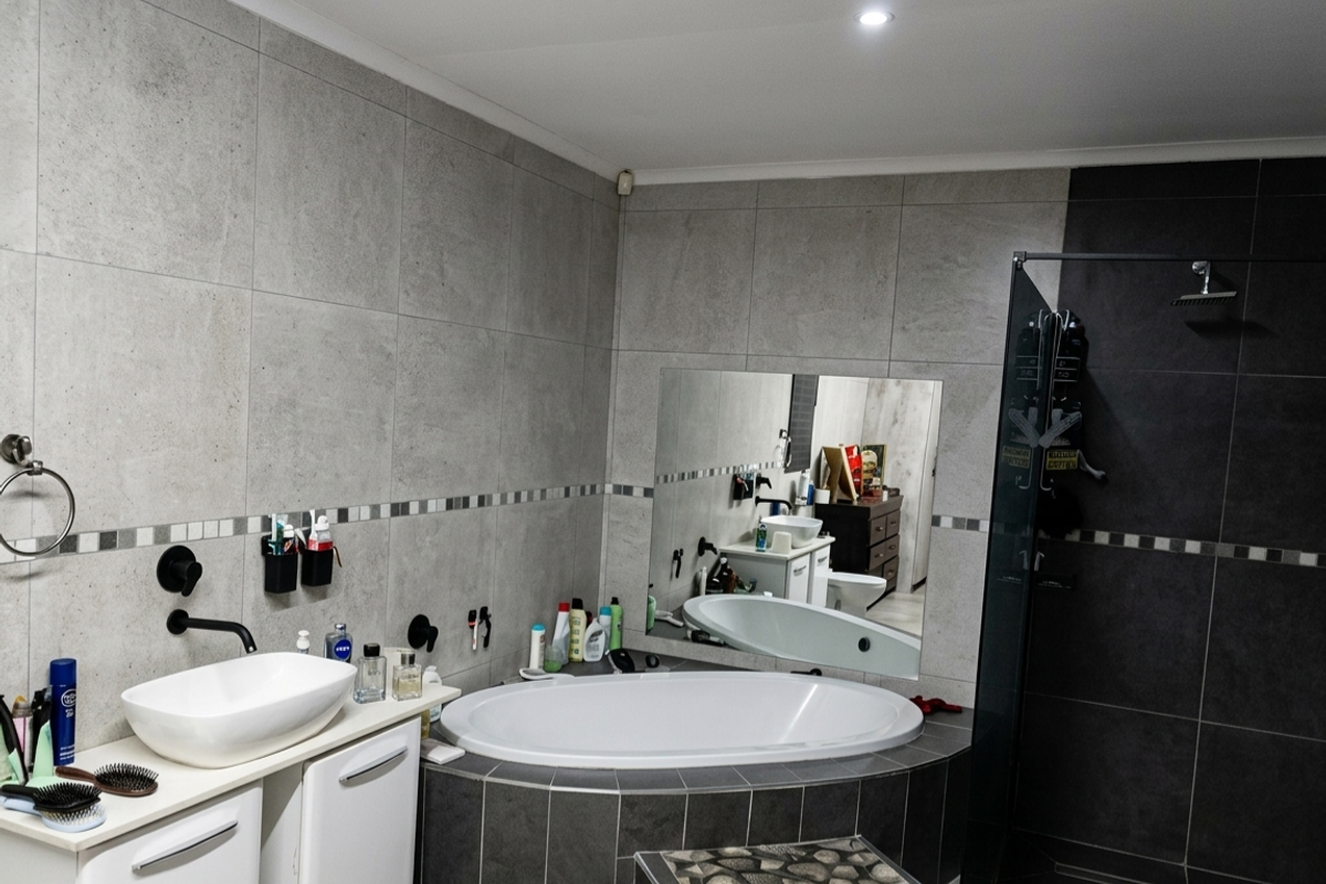 Modern bathroom featuring a tiled walk-in shower, a built-in bathtub with dark tile surround, and a contemporary vessel sink vanity.