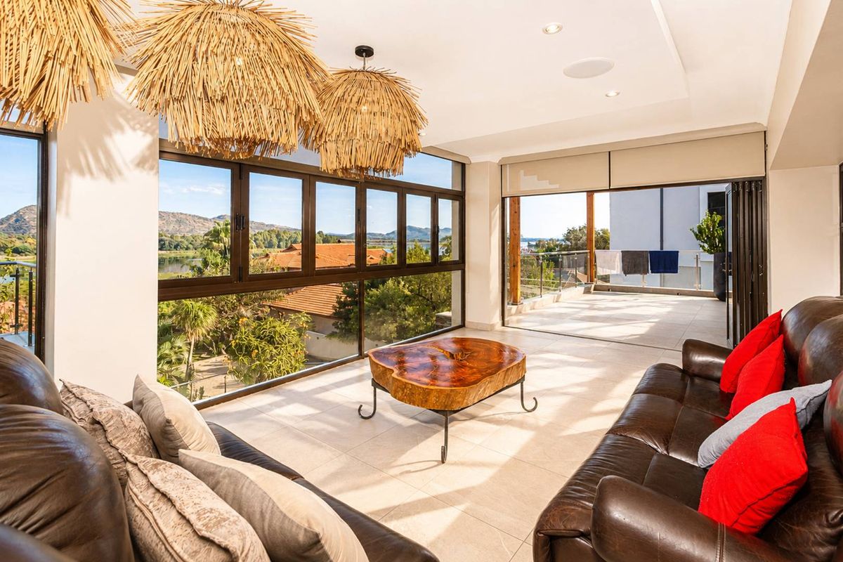 Bright living area featuring large windows with scenic views, tiled flooring, recessed lighting, and seamless access to an outdoor patio space.