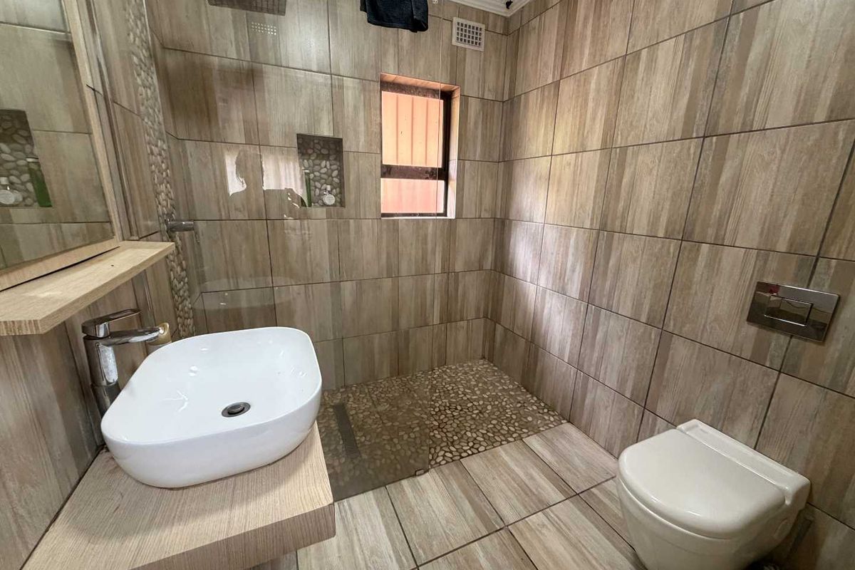 Modern bathroom featuring wood-look floor and wall tiles, a floating vanity with a vessel sink, a wall-mounted toilet, and a walk-in shower.