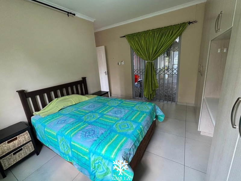 A bedroom featuring tiled flooring, built-in cupboards, and a sliding door with a security gate leading to an outdoor area.