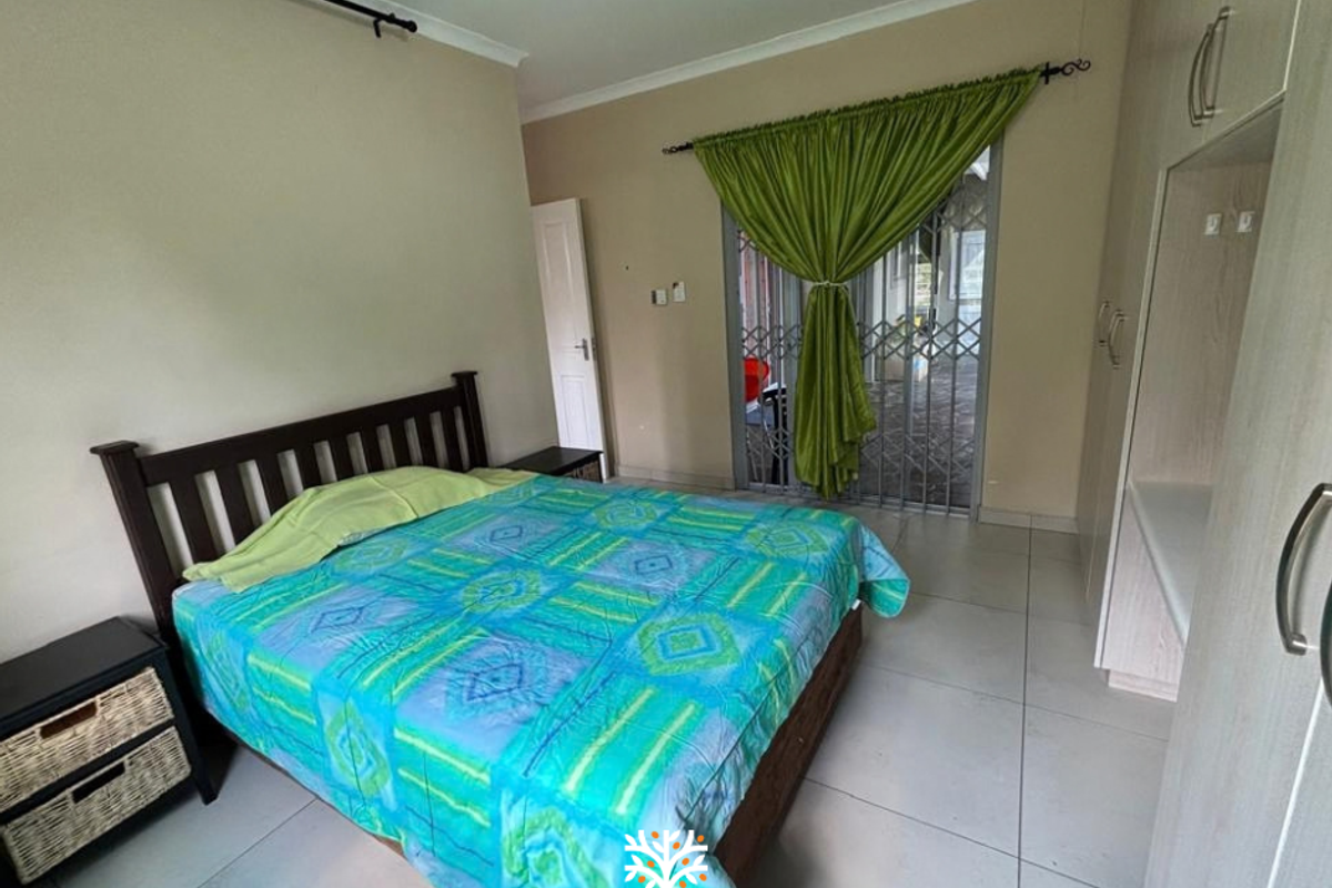 A bedroom featuring tiled flooring, built-in cupboards, and a sliding door with a security gate leading to an outdoor area.