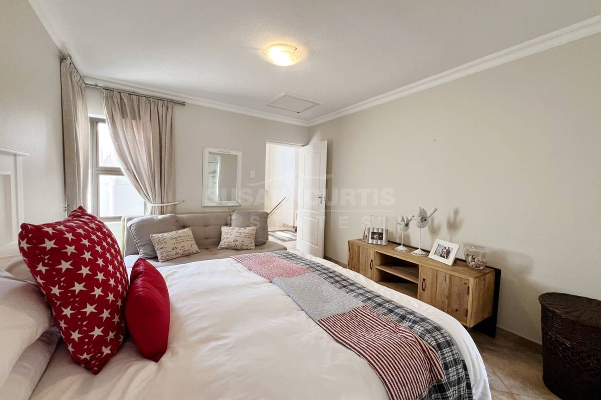 A well-lit bedroom featuring tiled flooring, crown molding, and a neutral color palette, providing a comfortable and functional living space.