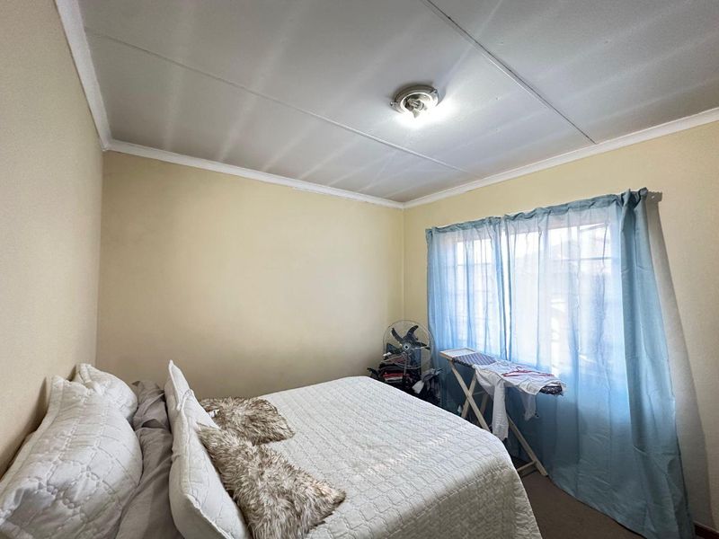 A bedroom featuring a standard layout with ceiling tiles and a window, requiring cosmetic updates to improve the overall finish and appeal.