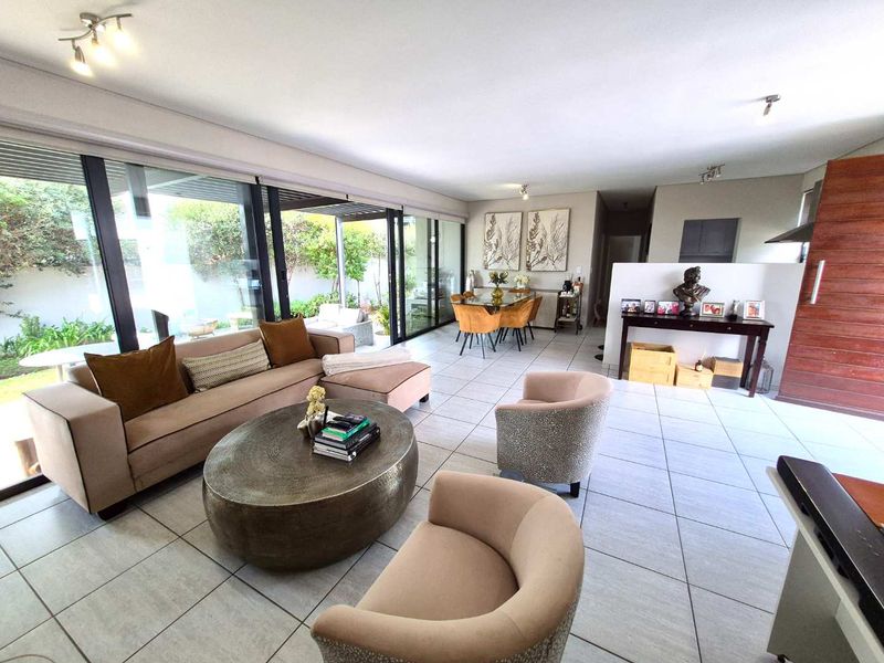 Spacious open-plan living and dining area featuring large sliding glass doors that provide seamless access to the outdoor patio and garden.