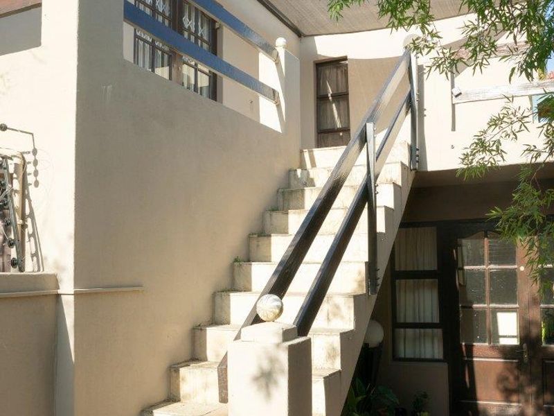 Exterior view of an apartment building featuring an external staircase leading to an upper-level balcony and a ground-floor entrance.