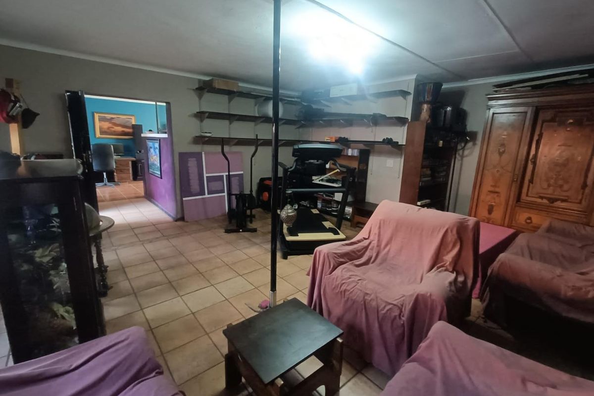 A spacious living area featuring tiled flooring, built-in wall shelving, and a central support pole, offering potential for renovation and modernization.