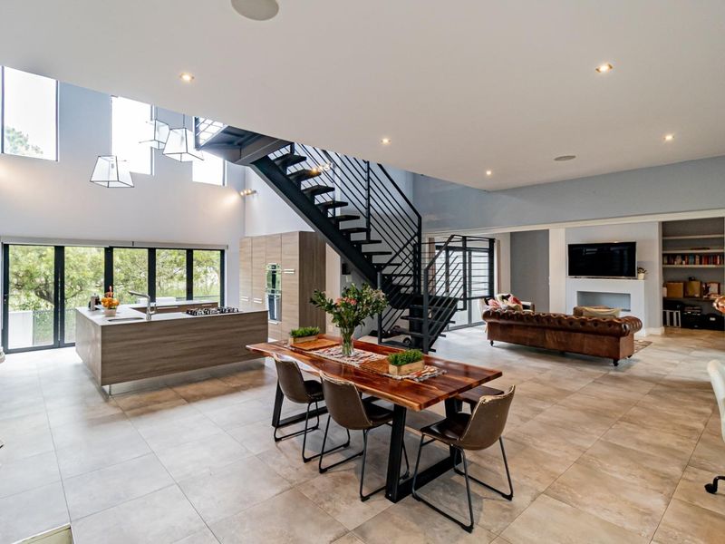 Spacious open-plan living area featuring a modern kitchen with island, sleek metal staircase, tiled floors, and a cozy fireplace with built-in shelving.