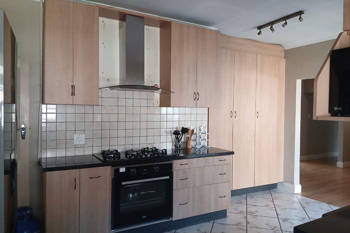 A functional kitchen featuring light wood cabinetry, granite countertops, a gas hob, and an electric oven, with tiled flooring and backsplash.